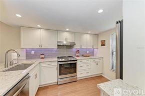 Bradenton condo for rent - A kitchen with white cabinets and a stainless steel refrigerator.