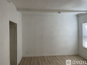Seattle apartment for rent - A room with wooden flooring and white walls, with a door on the left and a window on the right.