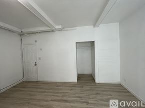 Seattle apartment for rent - A room with wooden flooring and white walls, with a door on the left and a partially visible door on the right.