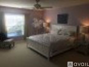 Naples condo for rent - A bedroom with a bed, a chair, and a ceiling fan.