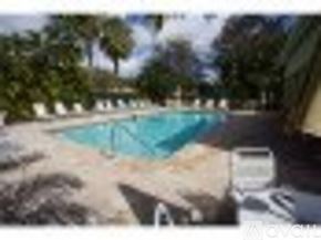 Naples condo for rent - A pool surrounded by trees and a white fence.
