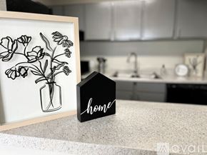 Victoria apartment for rent - A framed drawing of flowers sits on a countertop next to a small black house-shaped sign that says "home.".
