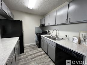 Victoria apartment for rent - A kitchen with black appliances and grey cabinets.