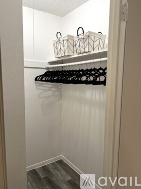 Victoria apartment for rent - A white closet with black hangers and white baskets on top.