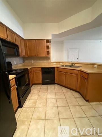 West Palm Beach condo for rent - A kitchen with wooden cabinets and black appliances.