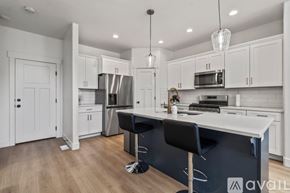 Lehi apartment for rent - A kitchen with white cabinets and a black island.