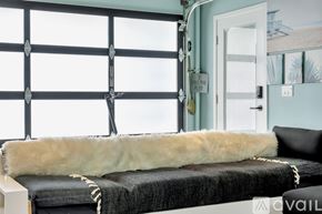 El Segundo apartment for rent - A bedroom with a bed covered in a black blanket and a white fur throw.
