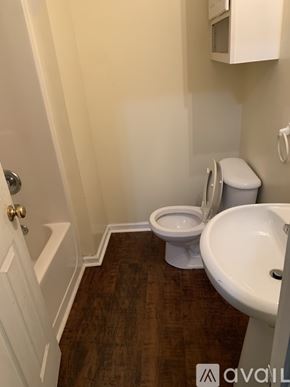 Riverdale house for rent - A white toilet sits next to a white sink in a small bathroom.