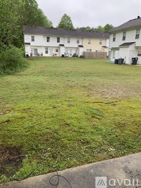 Riverdale house for rent - A grassy area in front of a white house with a black roof.