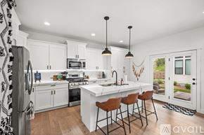 Midvale townhouse for rent - A kitchen with white cabinets and a white island with brown chairs.