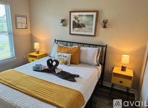 Gulfport apartment for rent - A bedroom with a bed, two lamps, and a picture on the wall.