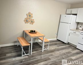 Gulfport apartment for rent - A kitchen with a table and chairs in the foreground and a refrigerator in the background.