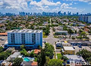 Miami apartment for rent - A large white building with a pool in front of it is the main focus of this image.