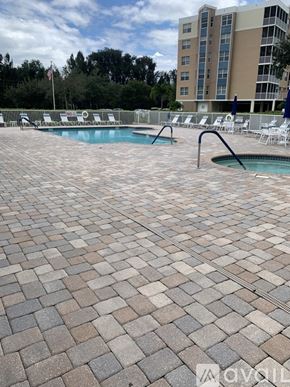 Largo condo for rent - A pool surrounded by a brick patio with chairs and a building in the background.