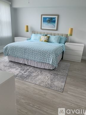 Largo condo for rent - A bed with a blue and white patterned comforter is in the center of a bedroom with a white headboard and two lamps on either side of the bed.
