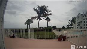 Vero Beach condo for rent - A view from a balcony overlooking a pool and palm trees.