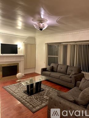 Los Angeles house for rent - A living room with a grey couch, a glass coffee table, and a television.