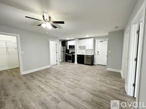 Chicago apartment for rent - A spacious room with a ceiling fan and lighting fixture, featuring a kitchenette with a refrigerator, microwave, and oven.