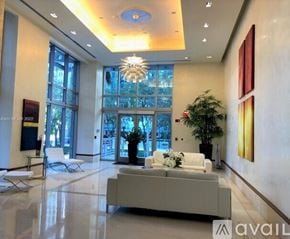 Miami apartment for rent - A spacious lobby with a white sofa, a potted plant, and a chandelier.