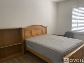 Corona apartment for rent - A bedroom with a bed, wooden headboard, and a chair.