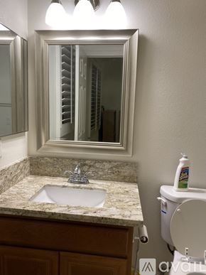 Corona apartment for rent - A bathroom with a marble countertop and a mirror above the sink.