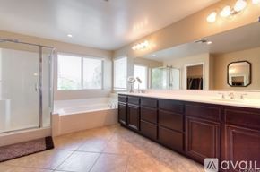 Corona apartment for rent - A bathroom with a large mirror, double sinks, and a walk-in shower.