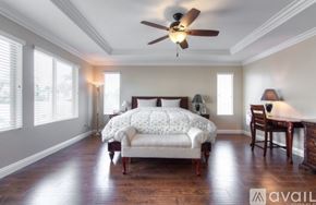 Corona apartment for rent - A bedroom with a bed, chair, and a ceiling fan.