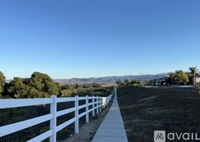 Lompoc apartment for rent - A white fence runs along a path in a grassy area.