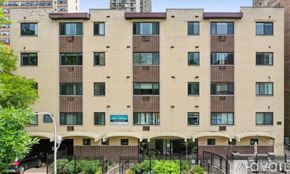 Chicago apartment for rent - A large beige building with a black fence in front.