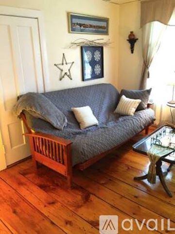Newburyport apartment for rent - A living room with a grey couch and a wooden chair.