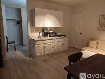 Marina apartment for rent - A kitchen with white cabinets and a wooden floor.