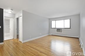 Chicago apartment for rent - A spacious room with wooden flooring and a window with blinds.