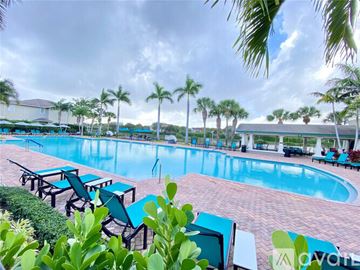 West Palm Beach townhouse for rent - A pool surrounded by palm trees and lounge chairs.