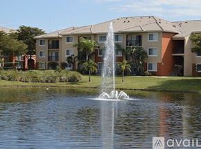 West Palm Beach condo for rent - A fountain in the foreground of a grassy area in front of apartment buildings.