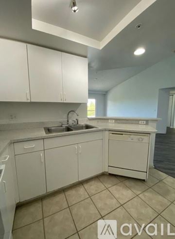 West Palm Beach condo for rent - A kitchen with white cabinets and a tiled floor.