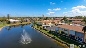 Naples condo for rent - A fountain in the middle of a lake in front of a building.