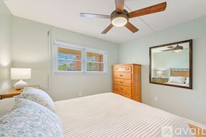 Naples condo for rent - A bedroom with a large bed, a ceiling fan, and a dresser with a mirror above it.