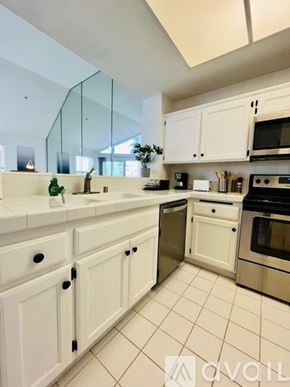 Huntington Beach condo for rent - A kitchen with white cabinets and a glass backsplash.