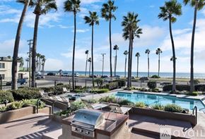 Huntington Beach condo for rent - A backyard with a pool, grill, and palm trees.