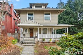 Tacoma apartment for rent - A two-story house with a front porch and a white picket fence.