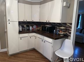 Syracuse apartment for rent - A kitchen with white cabinets and a black countertop.
