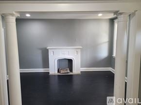 Baltimore house for rent - A white fireplace in a room with grey walls and black flooring.