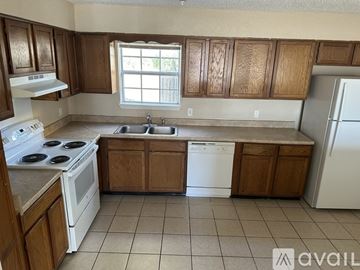 North Richland Hills apartment for rent - A kitchen with wooden cabinets and white appliances.
