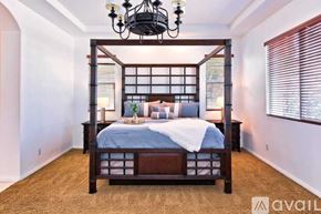 Palm Desert house for rent - A bedroom with a four-poster bed and a chandelier.