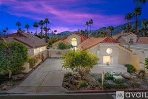 La Quinta house for rent - A house with a driveway and palm trees in the background.