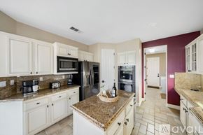 La Quinta house for rent - A kitchen with white cabinets and a granite countertop.