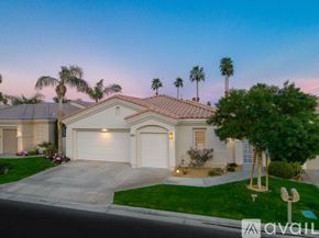 La Quinta house for rent - A house with a driveway and palm trees in front.