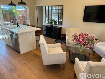 Napa apartment for rent - A living room with a white sofa, a white chair, and a glass coffee table with flowers on it.