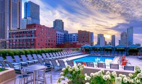 Chicago condo for rent - A rooftop pool area with lounge chairs and a table surrounded by buildings.