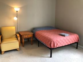Apopka apartment for rent - A bedroom with a bed, chair, and nightstand.